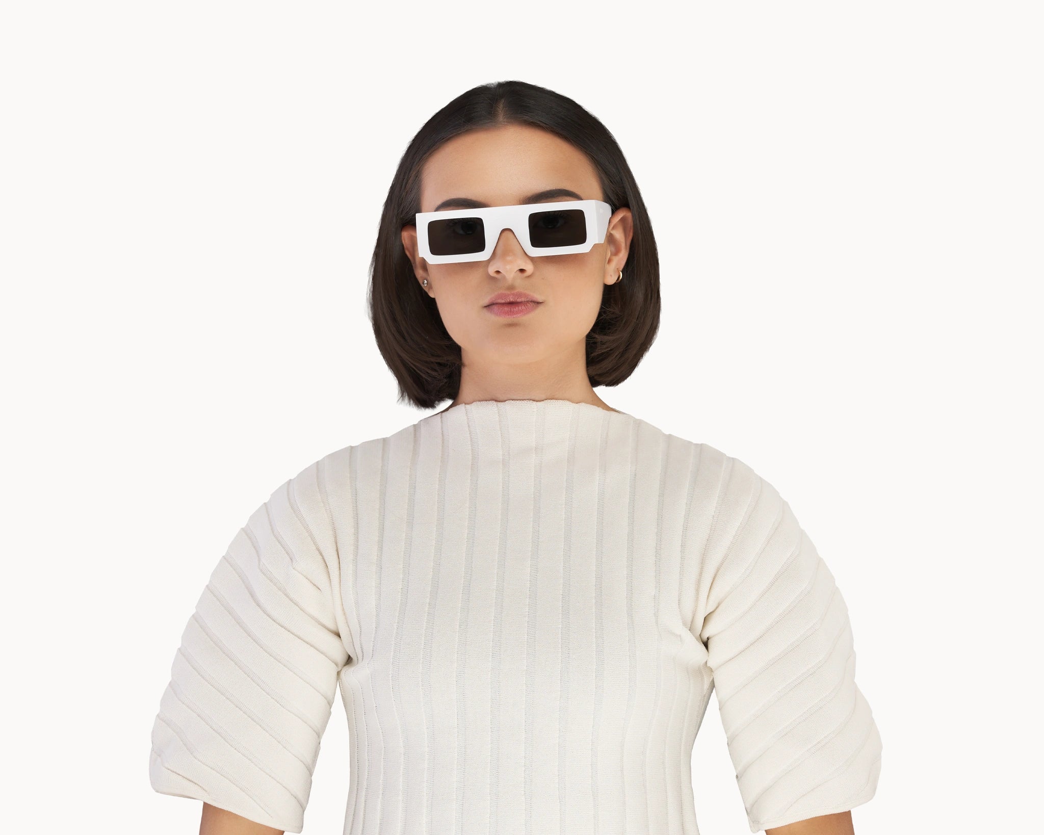 Kvinnelig modell med ikoniske 3D-inspirerte hvite retro-solbriller fra VIDAR EYEWEAR.